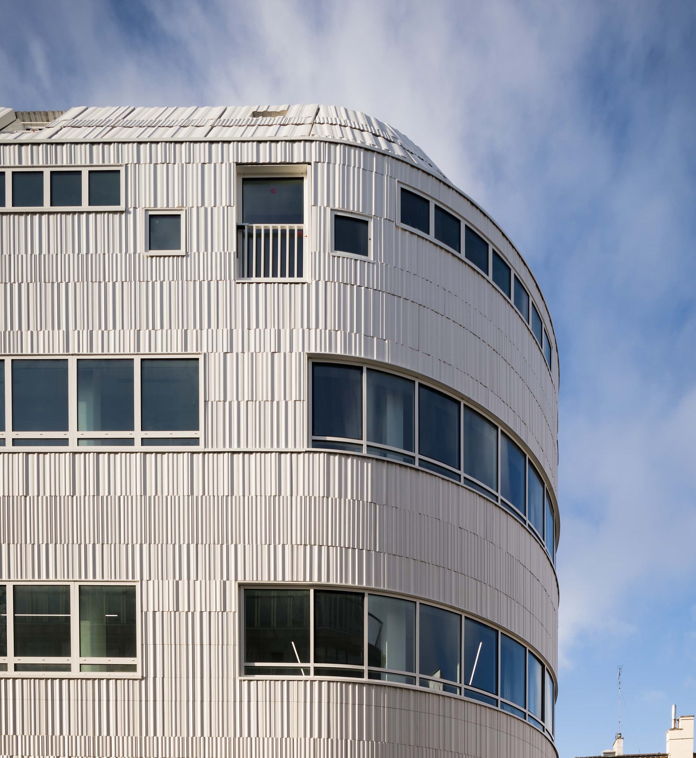 Habillage de façade courbe en dalles minérales Rebeton sur mesure – projet Lucie Faure.